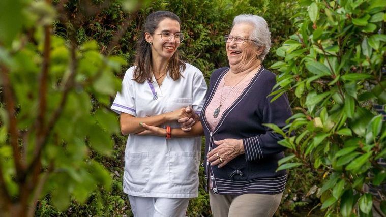 Una profesional de DomusVi pasea con una residente.