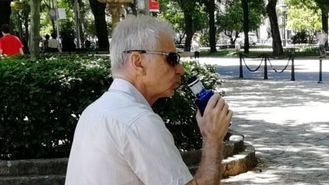 Hidratación, una persona mayor bebe agua en el parque.