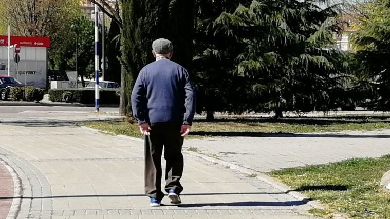 Una persona mayor pasea por un parque.