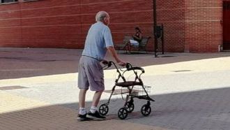 Una persona mayor dependiente pasea por la calle.