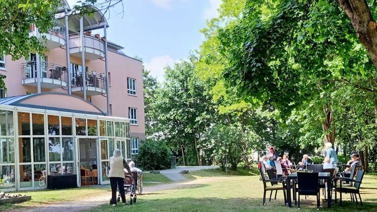 Personas mayores en el jardín de una residencia.