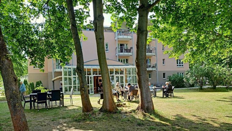 Personas mayores en el jardín de una residencia.